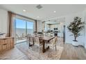 Elegant dining area with patio access, modern furnishings, and view into kitchen at 16381 W Weeping Willow Rd, Surprise, AZ 85387