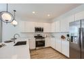 Well-equipped kitchen with stainless steel appliances, white cabinets, quartz countertops, and tile flooring at 16722 W Audrey Ln, Surprise, AZ 85387