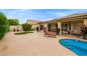 Spacious backyard features a pool, covered patio, lounge chair, and lush landscaping at 17718 N Desert Flower Trl, Surprise, AZ 85374