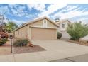 Tan home showing the garage, partial front, desert landscaping and a beautiful sky at 2112 E Donald Dr, Phoenix, AZ 85024