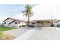This is a home with a long driveway leading to a covered parking area and a palm tree at 6445 W Windsor Blvd, Glendale, AZ 85301