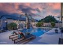 Backyard pool with lounge chairs, palm trees, and string lights providing a relaxing outdoor space at 8544 W Mary Ann Dr, Peoria, AZ 85382