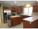 Well-equipped kitchen with stainless steel appliances, wood cabinets, and center island at 9203 W Behrend Dr, Peoria, AZ 85382