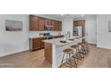 Stylish kitchen featuring granite countertops, wood flooring, stainless appliances, and island with seating at 9853 E Solstice Ave, Mesa, AZ 85212