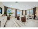 Bright and airy living room with neutral tones, tile floors, large windows, modern furnishings, and outdoor access at 10049 E Ulysses Ave, Mesa, AZ 85212
