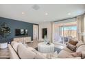 Cozy living room featuring a blue accent wall, comfortable seating, and a sliding glass door to the patio at 15791 W Kendall St, Goodyear, AZ 85338