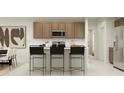 Modern kitchen features an island with barstool seating, stainless steel appliances, and wood cabinetry at 23207 W Marguerite Ave, Buckeye, AZ 85326