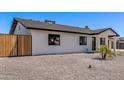 Side view of a modern white home with a dark roof, stylish landscaping, and wooden fence at 2926 E Corrine Dr, Phoenix, AZ 85032