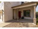 Covered front porch with decorative columns, a red front door, and gravel landscaping at 3491 N 301St Dr, Buckeye, AZ 85396