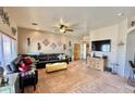 Spacious living room with saltillo tile, black leather sofa, neutral paint, and a ceiling fan at 36721 N 17Th Ave, Phoenix, AZ 85086