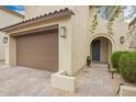 Beautiful tan home with a tile roof, desert landscaping, and a two-car brown garage door at 10050 E Texas Ave, Mesa, AZ 85212
