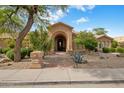 Inviting home exterior featuring an arched entryway and well-maintained desert landscaping at 10892 E Gold Dust Ave, Scottsdale, AZ 85259