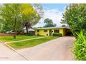 Quaint yellow home features lush landscaping and covered parking, adding charm and functionality at 1609 E Williams N St, Tempe, AZ 85281