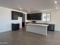 Modern kitchen featuring dark wood cabinetry, a spacious island, stainless steel appliances, and tile flooring at 18418 W Monte Lindo Ln, Surprise, AZ 85387