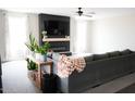 Bright living room featuring a sleek fireplace, a ceiling fan, and a comfortable sectional sofa at 19814 W Buchanan St, Buckeye, AZ 85326
