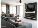 Cozy living room with a large gray sectional sofa, a fireplace with a TV, and bright natural light at 19814 W Buchanan St, Buckeye, AZ 85326
