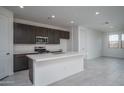 Modern kitchen with stainless steel appliances, a large island with a sink, and sleek, dark-stained cabinets at 2823 N 212Th Dr, Buckeye, AZ 85396