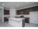 Modern kitchen with stainless steel appliances, a large island with a sink, and sleek, dark-stained cabinets at 2823 N 212Th Dr, Buckeye, AZ 85396