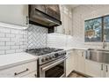 Modern kitchen featuring stainless steel stove with decorative hood and bright white subway tile at 2851 W Gold Dust Ave, San Tan Valley, AZ 85144