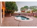 A backyard oasis featuring a private pool, mature trees, an umbrella, and decorative string lights at 288 W Los Alamos St, Gilbert, AZ 85233