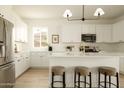 Beautiful open kitchen with stainless appliances, white cabinets, ample counter space, and stylish pendant lighting at 3047 S Chatsworth --, Mesa, AZ 85212