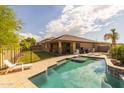 Spacious backyard featuring a refreshing swimming pool, lush lawn and covered patio seating area at 517 S 165Th Dr, Goodyear, AZ 85338