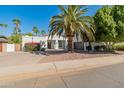 Charming single-story house showcasing desert landscaping, a lush green tree, and a spacious circular driveway at 6220 E Paradise Ln, Scottsdale, AZ 85254