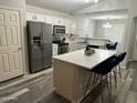Kitchen with stainless steel appliances, an island with seating, and gray wood floors at 6920 S 46Th Dr, Laveen, AZ 85339