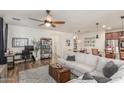 Spacious living room featuring hardwood floors, ceiling fan, a workstation and a large couch at 13720 W Amberwing St, Peoria, AZ 85383