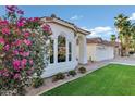 Charming white home with beautiful flower landscaping and green grass, with a beautiful red tile roof at 16662 S 37Th Way, Phoenix, AZ 85048