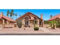 Inviting single-story home with desert landscaping and a tiled roof, surrounded by lush palm trees and vibrant greenery at 1910 E Citation Ln, Tempe, AZ 85284