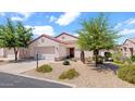 Inviting single-story home featuring desert landscaping, a tile roof, and an attached two-car garage at 19523 N Carriage Ln, Surprise, AZ 85374