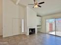 Open-concept living room showcasing vaulted ceilings, tile floors, a fireplace, and access to the backyard at 2100 W Lemon Tree Pl # 59, Chandler, AZ 85224