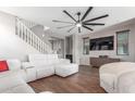 Bright living room featuring a sleek ceiling fan, a television, and a white sofa, with a staircase on the side at 4135 E Waterman Ct, Gilbert, AZ 85297