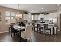Open kitchen featuring white cabinetry, granite countertops, stainless steel appliances and dining area at 41413 W James Ln, Maricopa, AZ 85138