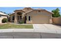 Well-manicured home featuring a beige exterior, arched entryway, and attached two-car garage at 5010 W Ivanhoe St, Chandler, AZ 85226