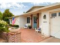 Inviting front entrance with brick porch, seating, an American flag, and vibrant flowers at 6311 E Calle Rosa --, Scottsdale, AZ 85251