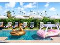 Backyard pool with fun floats, lounge chairs, and umbrellas creates a playful summer vibe at 8734 E Amelia Ave, Scottsdale, AZ 85251