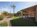 Private backyard featuring an outdoor living space, artificial grass, and lush desert landscaping at 10371 W Pontiac Dr, Peoria, AZ 85382