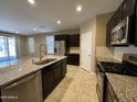 Modern kitchen featuring stainless steel appliances, dark cabinets, and a granite countertop island at 10743 W Bronco Trl, Peoria, AZ 85383