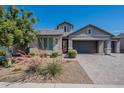 Beautiful single-story home featuring a three-car garage and lush landscaping with brick accents on the facade at 11656 W Luxton Ln, Avondale, AZ 85323