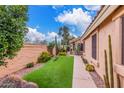 Side yard featuring desert landscaping, gravel, synthetic grass, cacti, and walkway; blending natural beauty with low maintenance at 12686 N 95Th Way, Scottsdale, AZ 85260