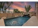 Backyard pool featuring a rock waterfall feature and lush landscaping at 14744 W Poinsettia Dr, Surprise, AZ 85379