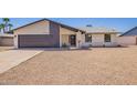 Charming single-story home featuring a gravel yard, gray garage door, and modern architecture under a clear sky at 17040 N 39Th Ave, Glendale, AZ 85308