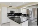 Modern kitchen with white cabinets, stainless steel appliances, an island, and black countertops at 20734 N 38Th St, Phoenix, AZ 85050