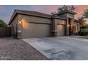 Spacious three-car garage with a concrete driveway and desert landscaping at 22166 N Lakeside Dr, Maricopa, AZ 85138