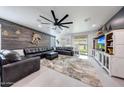 Spacious living room with a large sectional sofa, wood accent wall, and modern ceiling fan at 22282 N 184Th Ln, Surprise, AZ 85387