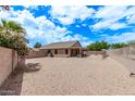 Expansive backyard with gravel landscaping, mature trees, covered patio, and block fence for privacy at 22683 N Aaron Rd, Maricopa, AZ 85138