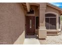Inviting front entryway featuring a decorative wood door, textured walls and tiled walkway at 22683 N Aaron Rd, Maricopa, AZ 85138