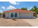 Charming single-story home featuring a red tile roof, arched windows, and a low-maintenance desert landscape at 4953 W Acoma Dr, Glendale, AZ 85306